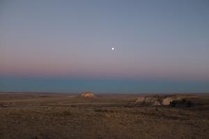 The moon and Pawnee Buttes landscape seen from dispersed camping in Pawnee National Grassland