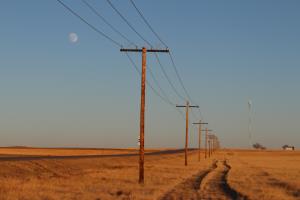 Side dirt road and powerlines in Pawnee National Grassland seen from paved road