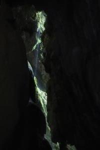 Narrow cracks in rock with waterfall seen looking up in chasm