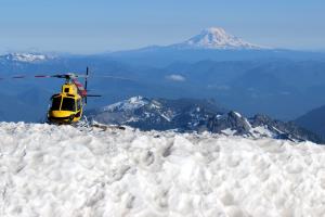 Rescue helicopter parked at Camp Muir with Mt. Adams in background