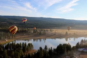 Four hot air balloons hovering near lake at festival