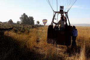 Hot air balloon pilot hovering over ground outside of festival camping area around 8:00AM