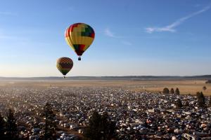 Hot air balloons hovering over festival camping area