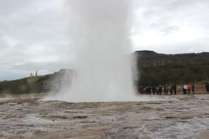 Strokkur erupting at Geysir with tourists watching