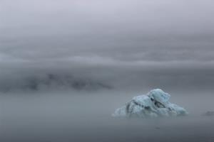 View of iceberg from land with fog covering land in background