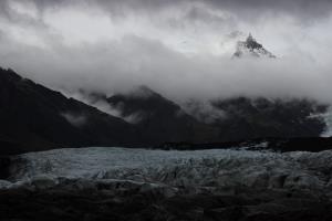 View of glacier with dark clouds and mountains