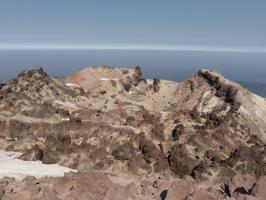 Snow on summit with smoke in distance covering landscape viewed from summit of Lassen Peak