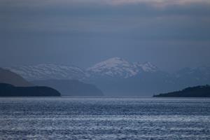 Distant snow covered mountains seen from boat outside Tromsø